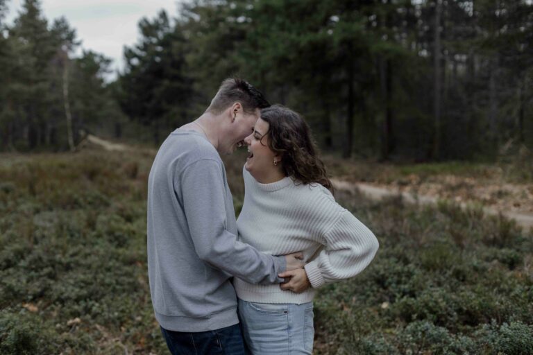 Een stralend koppel geniet van een loveshoot in Apeldoorn, waarbij ze door middel van fotografie prompts opdrachtjes oprechte momenten beleven en samen lachen voor de camera.