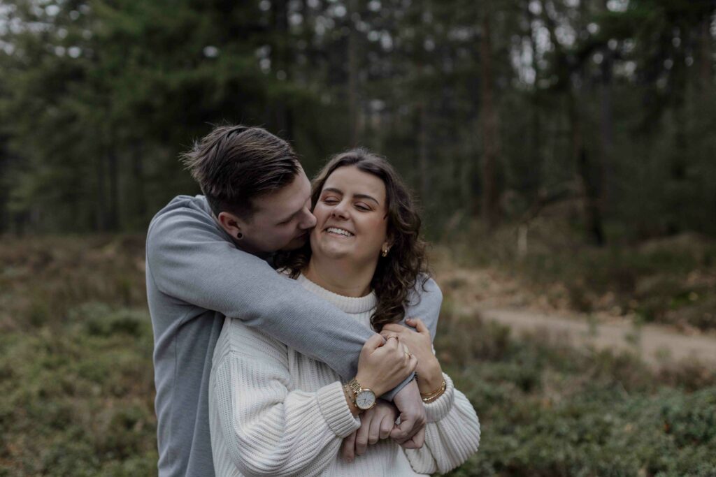 Een stralend koppel geniet van een loveshoot in Apeldoorn, waarbij ze door middel van opdrachtjes oprechte momenten beleven en samen lachen voor de camera.