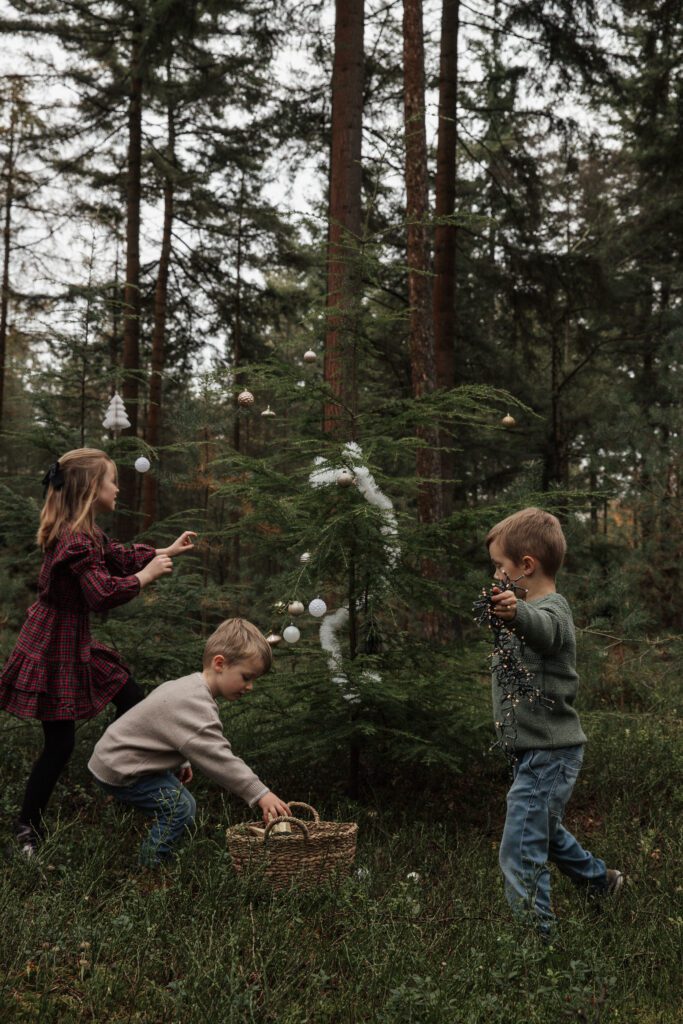 Gezin geniet van spontane kerstfotoshoot buiten met kerstboom en decoratie bij Van Dam Fotografie.