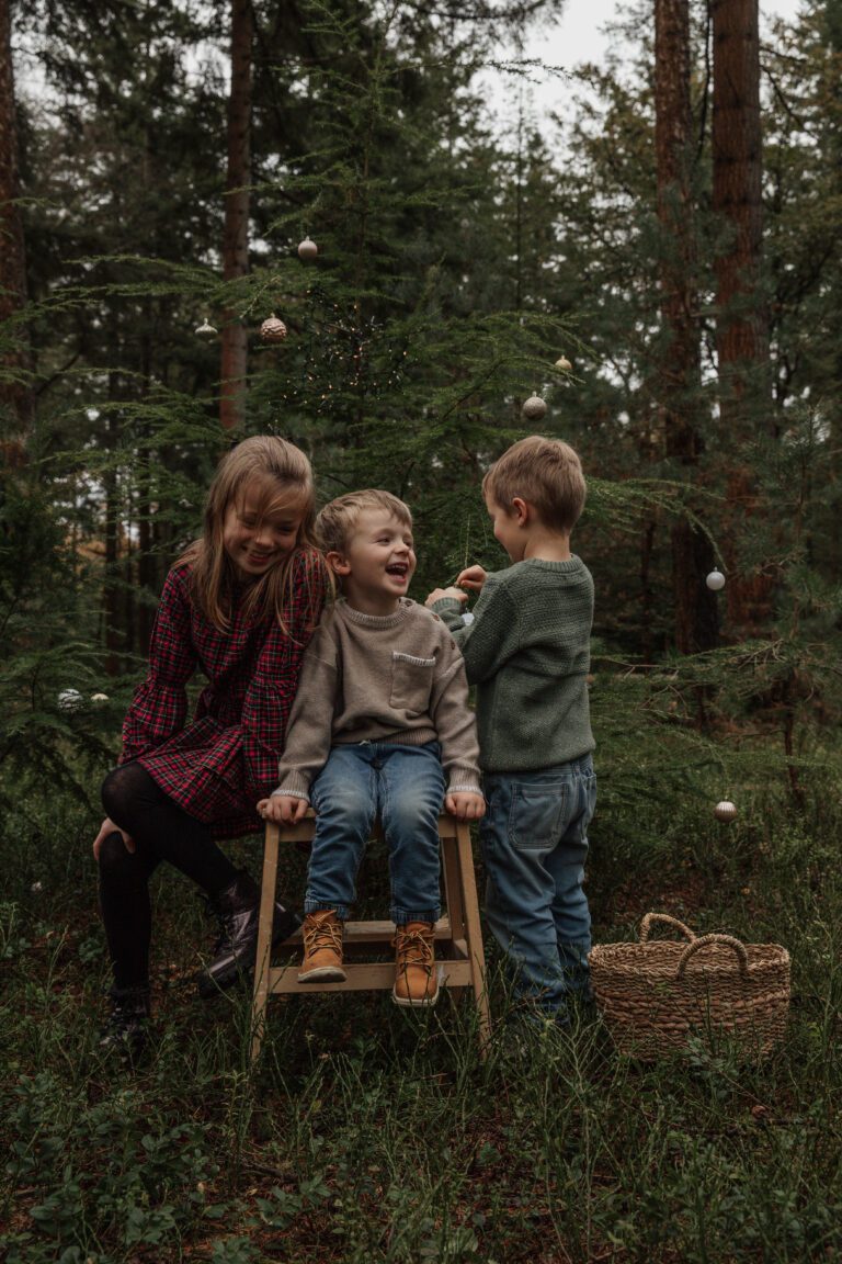 Gezin geniet van spontane kerstfotoshoot buiten met kerstboom en decoratie bij Van Dam Fotografie.