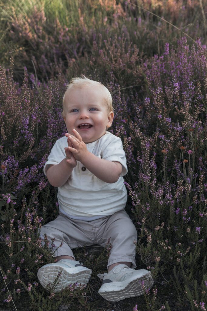Gezin tijdens fotoshoot op bloeiende paarse heide bij Het Leesten in Apeldoorn – spontane en betaalbare minishoot op de Veluwe in de zomer