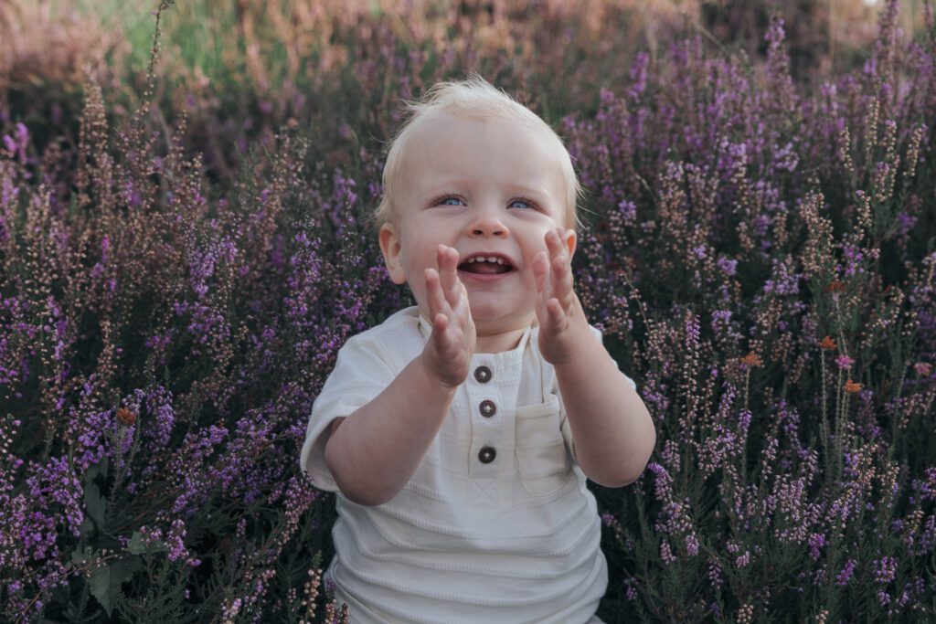 Gezin tijdens fotoshoot op bloeiende paarse heide bij Het Leesten in Apeldoorn – spontane en betaalbare minishoot op de Veluwe in de zomer
