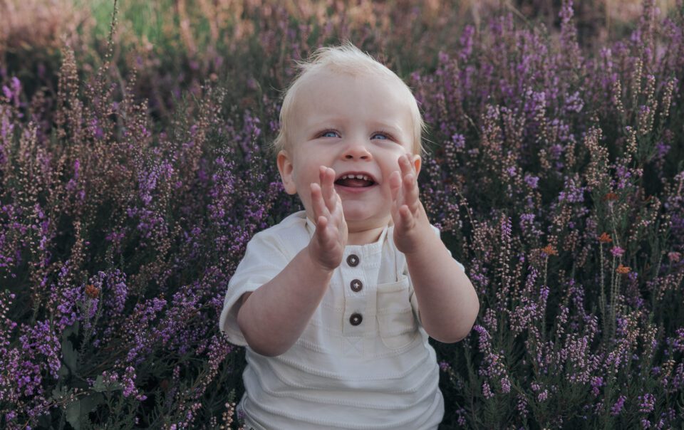 Gezin tijdens fotoshoot op bloeiende paarse heide bij Het Leesten in Apeldoorn – spontane en betaalbare minishoot op de Veluwe in de zomer