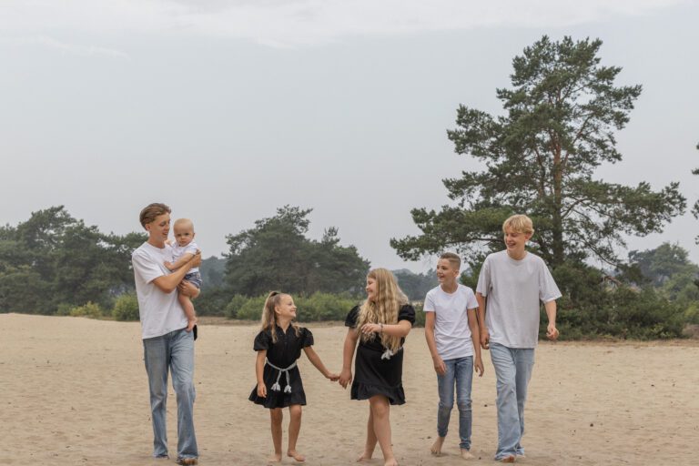 Broertje en zusje die elkaar vasthouden en lachen op het duin.