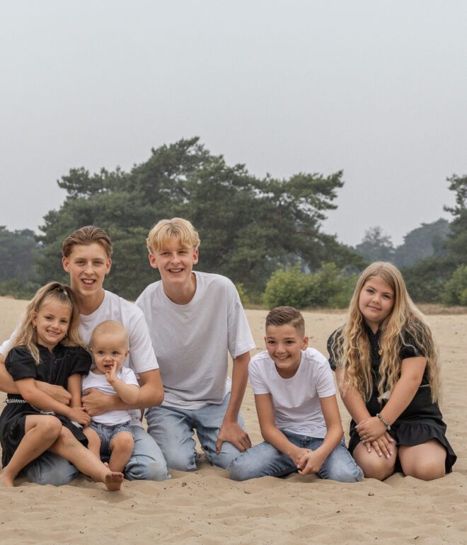 Kinderen van familie Wolvering tijdens een spontane fotoshoot op Kootwijkerduin, Apeldoorn, Gelderland, lachend en spelend tijdens creatieve opdrachtjes.