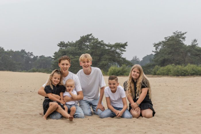 Kinderen van familie Wolvering tijdens een spontane fotoshoot op Kootwijkerduin, Apeldoorn, Gelderland, lachend en spelend tijdens creatieve opdrachtjes.