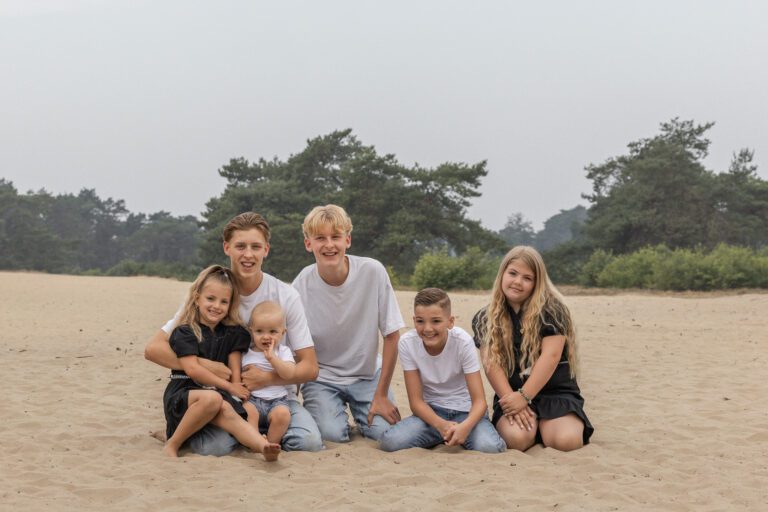 Kinderen van familie Wolvering tijdens een spontane fotoshoot op Kootwijkerduin, Apeldoorn, Gelderland, lachend en spelend tijdens creatieve opdrachtjes.