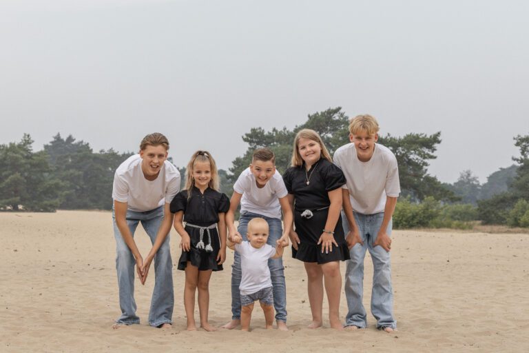 Kinderen van familie Wolvering tijdens een spontane fotoshoot op Kootwijkerduin, Apeldoorn, Gelderland, lachend en spelend tijdens creatieve opdrachtjes.