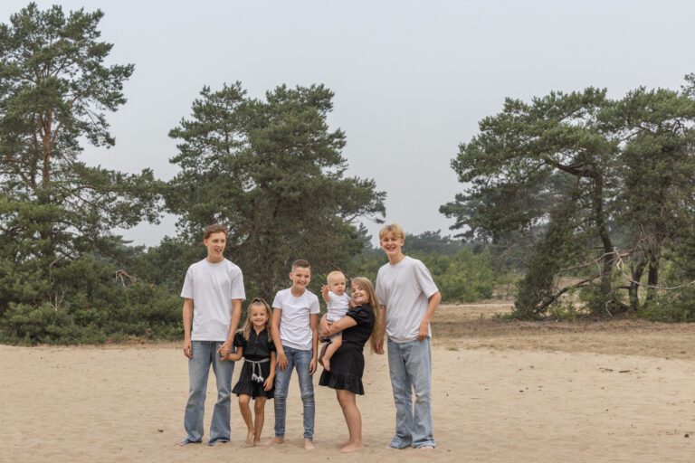 Kinderen van familie Wolvering tijdens een spontane fotoshoot op Kootwijkerduin, Apeldoorn, Gelderland, lachend en spelend tijdens creatieve opdrachtjes.
