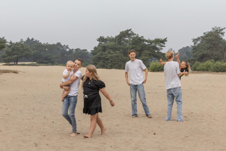 Kinderen spelend en lachend op het zandduin tijdens een fotoshoot.