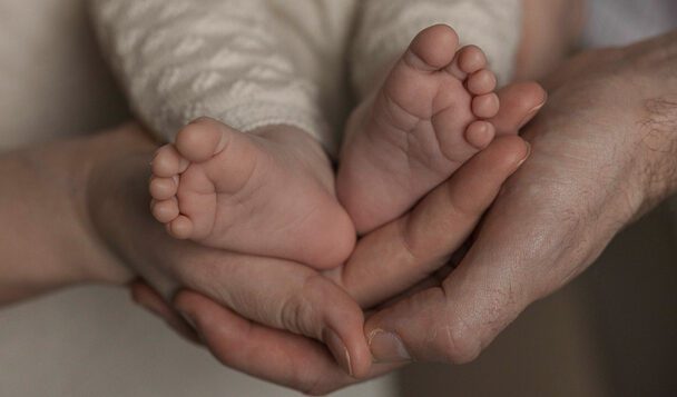Newbornfotograaf Apeldoorn – vader en moeder knuffelen met pasgeboren dochter voetjes baby handen