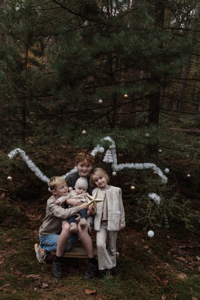 Kinderen versieren mini kerstboom tijdens kerstshoot Veluwe