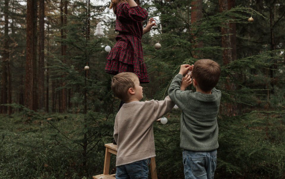 Kinderen versieren mini kerstboom tijdens kerstshoot Veluwe
