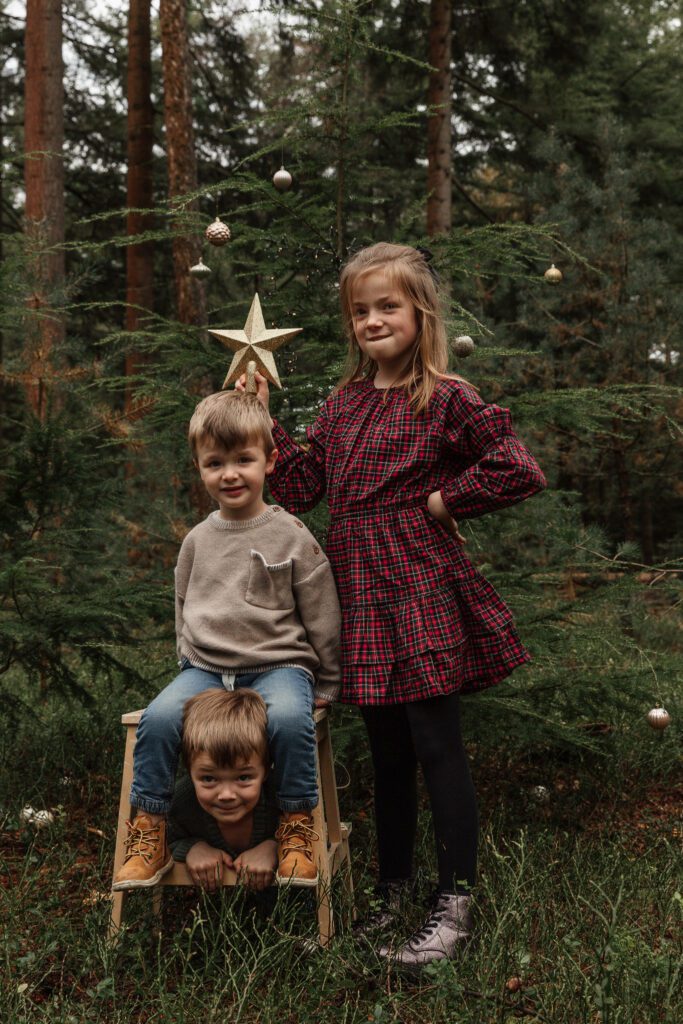 Kinderen versieren mini kerstboom tijdens kerstshoot Veluwe