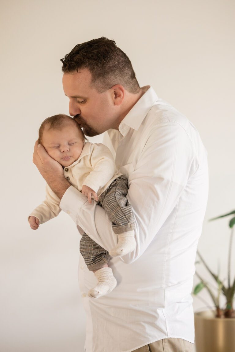 Liefdevolle moment tussen vader en baby tijdens newbornshoot